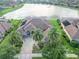 Aerial view of a home with lush landscaping, brick driveway, and a serene lake backdrop at 568 Luna Bella Ln, New Smyrna Beach, FL 32168
