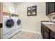 Laundry room with front loading washer/dryer, tile floors and utility sink at 568 Luna Bella Ln, New Smyrna Beach, FL 32168