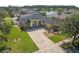 An aerial view of a single-story home with arched entryway, palm trees, a well-manicured lawn and a patterned concrete driveway at 3615 Marisol Ct, New Smyrna Beach, FL 32168