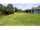 Expansive backyard with a waterway, lush green lawn, and partially screened patio at 516 Spotted Sandpiper Dr, Daytona Beach, FL 32119