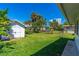 Lush backyard featuring palm trees, tropical landscaping, and a shed, offering plenty of space at 129 Dundee Rd, Daytona Beach, FL 32118