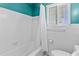 Clean and bright bathroom featuring a tiled shower-tub combo, toilet, and a window with blinds for natural light at 129 Dundee Rd, Daytona Beach, FL 32118