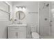 Bathroom with a tiled shower, updated fixtures, white cabinetry and a round, wood-trimmed mirror at 136 Reef Rd, South Daytona, FL 32119