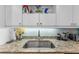 Kitchen close up featuring stainless steel sink with granite counters and white cabinets with hardware at 2934 Oceans Trce, Daytona Beach Shores, FL 32118