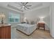 Bright bedroom with tray ceiling, ceiling fan, large window, and warm wood-look floors at 3029 Adrian Dr, Ormond Beach, FL 32174