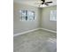 This bedroom features two windows, a ceiling fan, and stylish gray tile flooring at 992 Shockney Dr, Ormond Beach, FL 32174