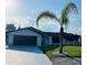 Charming single-story home with a well-manicured lawn, palm tree, and dark-colored garage door at 992 Shockney Dr, Ormond Beach, FL 32174