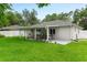 View of the back of the house with a covered patio and a well maintained lawn at 1719 Anniston Ave, Daytona Beach, FL 32117