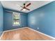 Bright blue bedroom with hardwood floors, ceiling fan, and natural light from a window at 2270 Wilmhurst Rd, Deland, FL 32720