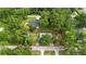 An aerial view of a single story house surrounded by mature trees with a driveway, grass and nearby street at 7686 Sw 81St St, Ocala, FL 34476