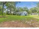 Backyard view of a light blue house showing lush green grass and tree coverage at 7686 Sw 81St St, Ocala, FL 34476