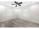 Bright bedroom featuring a ceiling fan, light gray wood-look flooring, and two windows at 7686 Sw 81St St, Ocala, FL 34476