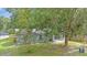 A charming single-story home with a light blue facade, set amid lush greenery and mature trees at 7686 Sw 81St St, Ocala, FL 34476