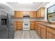 Bright kitchen with stainless steel refrigerator, white appliances, and wooden cabinets at 7686 Sw 81St St, Ocala, FL 34476