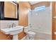 Bathroom with a pedestal sink, toilet, and bathtub with tiled walls and window at 902 Heron Point Cir, Deland, FL 32724