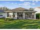 Back of house with a screened-in lanai overlooking well-maintained green lawn at 902 Heron Point Cir, Deland, FL 32724