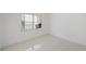 A clean bedroom with white walls and light tile flooring, showing a window overlooking a green area at 1 John Anderson Dr # 2180, Ormond Beach, FL 32176