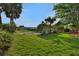 Expansive backyard with lush green grass, mature trees, and a glimpse of a tranquil lake at 101 Green Heron Ct, Daytona Beach, FL 32119