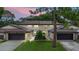 Charming townhome featuring an attached garage, well-maintained lawn, and beautiful landscaping at dusk at 12 Big Buck Trl, Ormond Beach, FL 32174