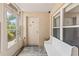 Welcoming front porch with white bench seating, tiled floor, and a storm door at 12 Big Buck Trl, Ormond Beach, FL 32174