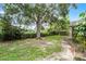 Lush backyard featuring large shade tree, plenty of room for activities, and a secure fence at 25216 Ironwedge Dr, Sorrento, FL 32776