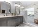 Beautifully renovated bathroom featuring a double vanity, marble countertops, and a glass-enclosed shower at 25216 Ironwedge Dr, Sorrento, FL 32776