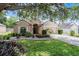 Single-story home featuring a well-kept lawn, a two-car garage, and a beautiful, mature tree at 25216 Ironwedge Dr, Sorrento, FL 32776
