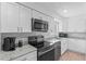 Modern kitchen with stainless appliances, granite counters, white cabinets, and tile backsplash at 321 Scotland Dr, Daytona Beach, FL 32117