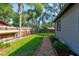 Fenced backyard with green grass, a gravel path, and mature trees at 35 Whippoorwill Ln, Ormond Beach, FL 32174