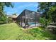 Serene backyard featuring a screened-in pool, lounge chairs, and a green lawn surrounded by lush tropical foliage at 1 Crooked Bridge Way, Ormond Beach, FL 32174