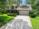 Traditional home boasting a manicured lawn, mature trees, and a two-car garage with brick accents at 1 Crooked Bridge Way, Ormond Beach, FL 32174