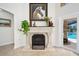 Elegant fireplace with white stone mantle, decorative accents, and a view through to the outdoor pool area at 1 Crooked Bridge Way, Ormond Beach, FL 32174