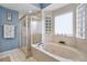 Bright bathroom featuring a large soaking tub, glass block window, and separate glass-enclosed shower at 11616 Sw 75Th Cir, Ocala, FL 34476