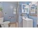 Bathroom with blue walls, a window, toilet, sink, and shower with grab bar at 1333 E Lombardy Dr, Deltona, FL 32725