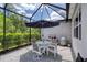 Cozy screened patio with outdoor dining set, patio umbrella and lush landscaping at 206 St Somewhere Dr, Daytona Beach, FL 32124