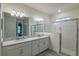 Bathroom featuring double sinks, a large mirror, modern lighting, and a glass-enclosed shower at 2861 Monaghan Dr, Ormond Beach, FL 32174