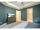 Bedroom featuring neutral walls, tray ceiling, dresser with TV, and ensuite bathroom access at 2861 Monaghan Dr, Ormond Beach, FL 32174