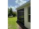 View of the screened porch with black screen, lush green grass and manicured landscaping at 2861 Monaghan Dr, Ormond Beach, FL 32174