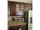Close-up of kitchen with dark wood cabinets, granite countertops, and stainless steel appliances at 3660 Daydream Pl, St Cloud, FL 34772