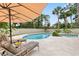 Relaxing backyard with pool, lounge chairs, umbrella, and mature landscaping at 428 Pelican Bay Dr, Daytona Beach, FL 32119