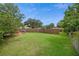 Large, well-maintained backyard with a wooden fence, featuring lush green grass and mature trees at 999 16Th St, Edgewater, FL 32132