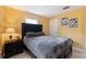 Bedroom with vibrant yellow walls, a plush grey bed set, and floral wall decor at 999 16Th St, Edgewater, FL 32132