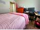 Cozy bedroom featuring a pink blanket, desk area with monitor, and natural light at 1561 Copperfield Ave, Deltona, FL 32738