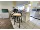 Kitchen view with tiled floors, breakfast bar with seating, white cabinets and stainless refrigerator at 1561 Copperfield Ave, Deltona, FL 32738