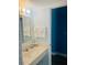 This bathroom features a white sink, mirror, towel rack, and blue accent wall at 1909 S Atlantic Ave # 405/406, Daytona Beach Shores, FL 32118