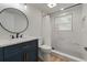 Bright bathroom featuring a new vanity, circular mirror, and tiled shower with glass window at 21375 Nw 150Th Avenue Rd, Micanopy, FL 32667