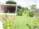 Lush backyard featuring a covered patio, well-manicured lawn, and blooming flowers, perfect for outdoor relaxation at 39 Benjamin Dr, Ormond Beach, FL 32176