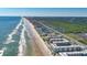 An aerial view shows a beachfront condominium complex next to the beach, Atlantic Ocean, and nearby neighborhood at 4155 S Atlantic Ave # 204, New Smyrna Beach, FL 32169