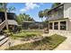 Landscaped backyard with stone pathway, tropical foliage, leading to a screened pool and elevated porch at 1108 Shockney Dr, Ormond Beach, FL 32174