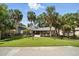 Charming home with a well-manicured lawn, mature palm trees, and a welcoming front porch at 1108 Shockney Dr, Ormond Beach, FL 32174